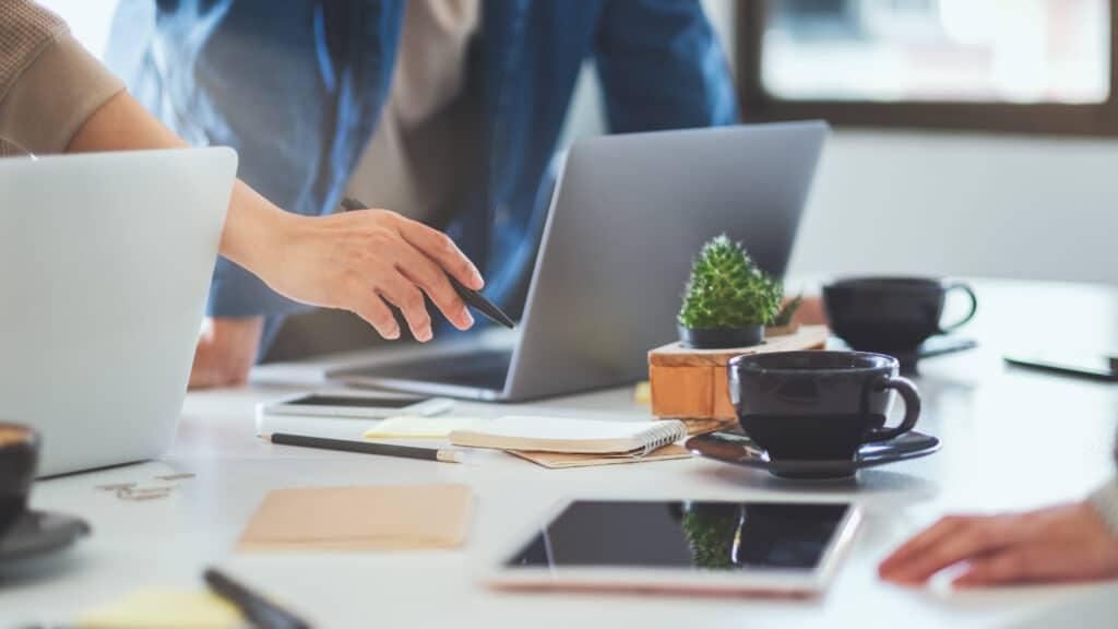 Corporate people around a table pointing at a laptop