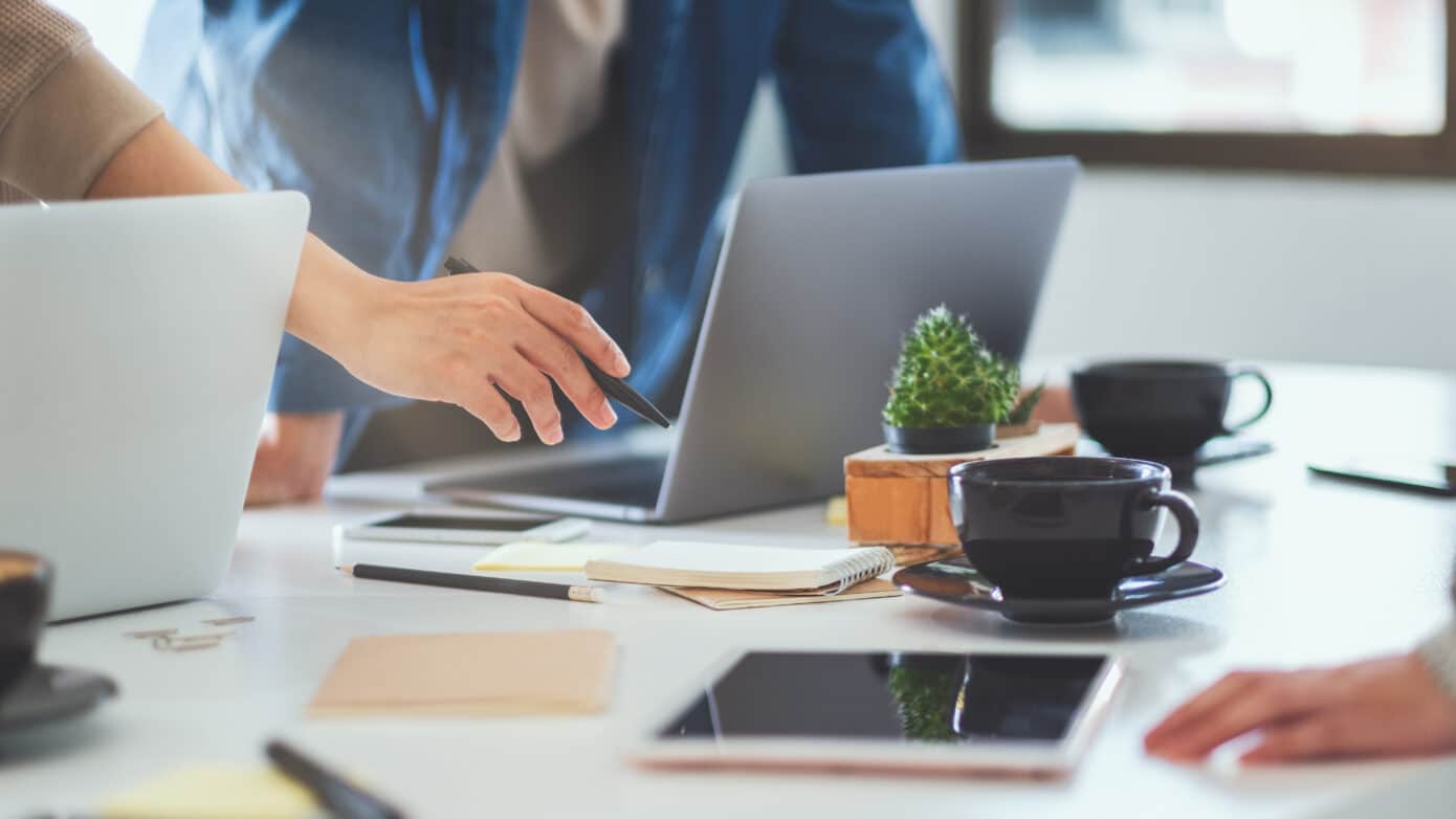 Corporate people around a table pointing at a laptop