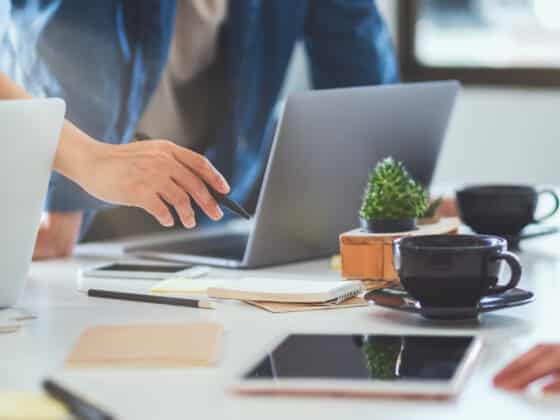 Corporate people around a table pointing at a laptop