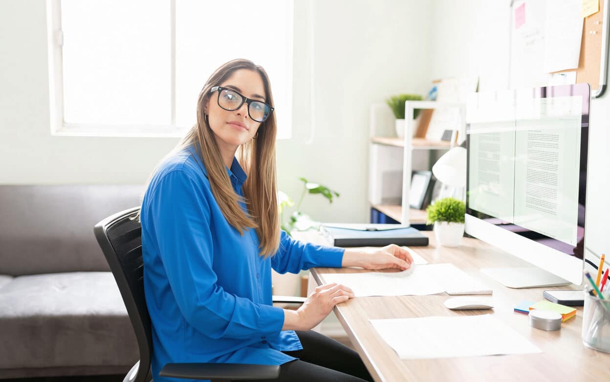 Content writer working in home office wearing a blue shirt and glasses.